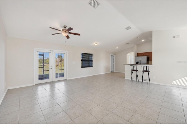 unfurnished living room featuring light tile patterned floors, french doors, vaulted ceiling, and ceiling fan