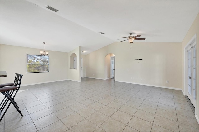 empty room with light tile patterned floors, ceiling fan with notable chandelier, and vaulted ceiling