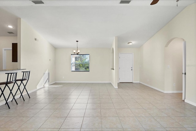 tiled spare room with ceiling fan with notable chandelier