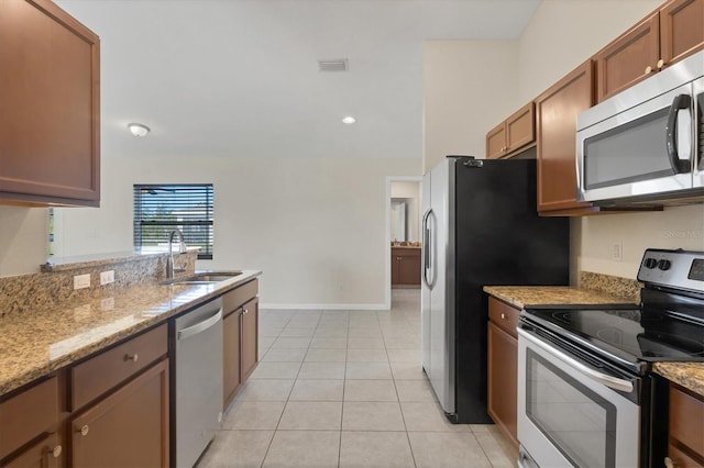 kitchen featuring light stone countertops, sink, light tile patterned floors, and stainless steel appliances