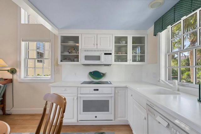 kitchen featuring white cabinets, white appliances, light hardwood / wood-style flooring, and sink