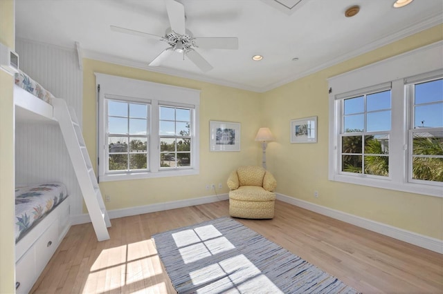 living area with ceiling fan, a healthy amount of sunlight, light hardwood / wood-style floors, and crown molding