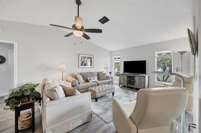 living room with ceiling fan, light hardwood / wood-style floors, and lofted ceiling