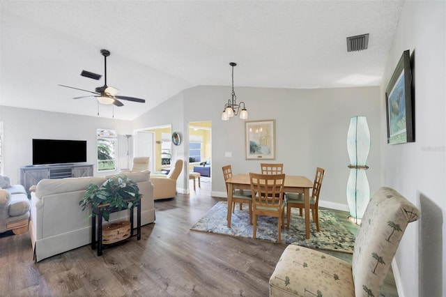 dining area featuring hardwood / wood-style flooring, ceiling fan with notable chandelier, and vaulted ceiling