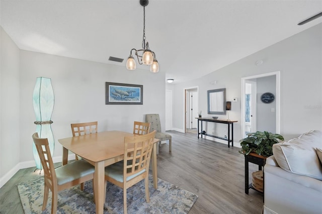 dining room featuring hardwood / wood-style floors, a notable chandelier, and vaulted ceiling