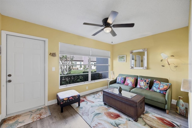 living room featuring ceiling fan, light hardwood / wood-style floors, and a textured ceiling