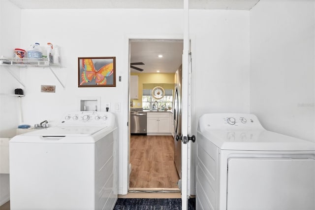 laundry room with washing machine and dryer, ceiling fan, sink, and wood-type flooring