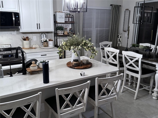 kitchen with decorative backsplash, a kitchen bar, and white cabinetry