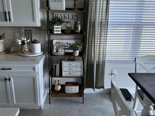 bar with white cabinets, decorative backsplash, and light tile patterned flooring