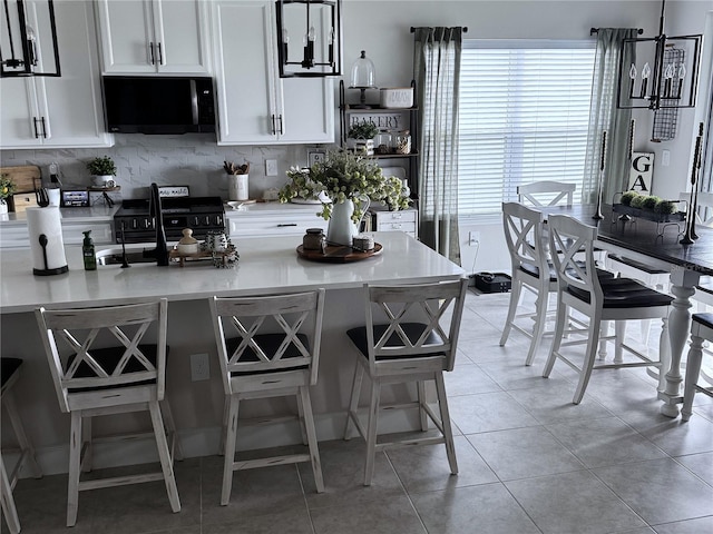 kitchen featuring white cabinets, black range with electric stovetop, plenty of natural light, and a breakfast bar area