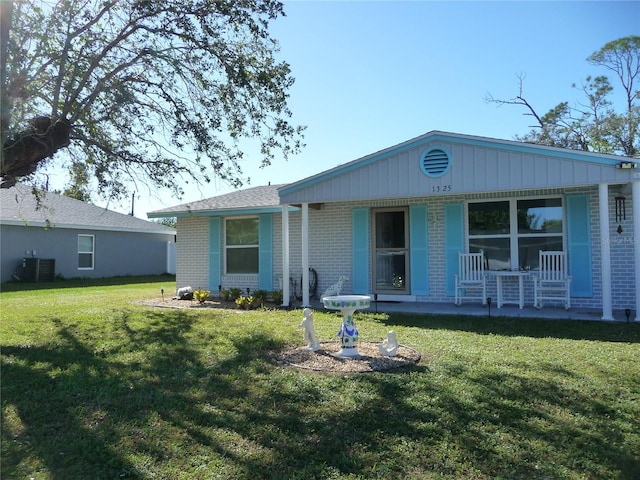 rear view of property featuring a porch, a yard, and cooling unit