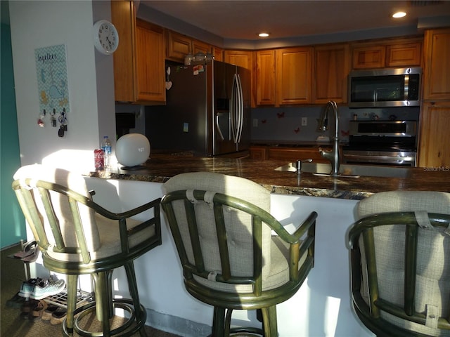 kitchen featuring kitchen peninsula, sink, dark stone countertops, and appliances with stainless steel finishes