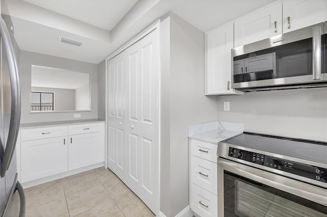 kitchen with white cabinets, light tile patterned flooring, and appliances with stainless steel finishes