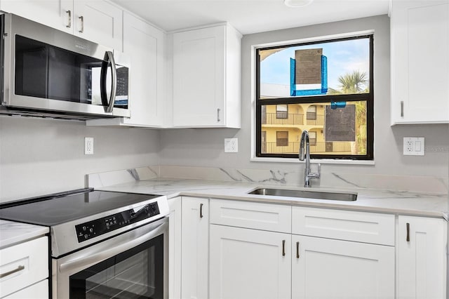 kitchen featuring white cabinets, light stone counters, sink, and appliances with stainless steel finishes