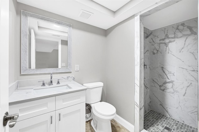 bathroom featuring vanity, toilet, and a tile shower