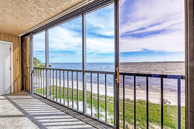 unfurnished sunroom with a view of the beach and a water view