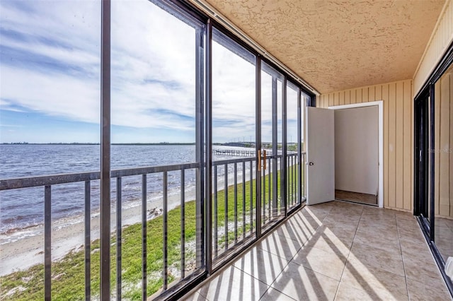 unfurnished sunroom featuring a view of the beach and a water view