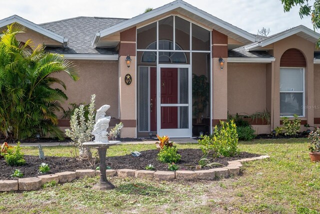 97 Mariner Ln, Rotonda West, FL 33947 - property entrance with stucco siding, roof with shingles, and a yard