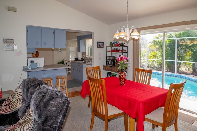 carpeted dining room featuring a chandelier, lofted ceiling, and sink