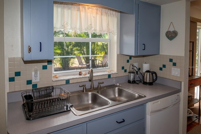 kitchen with dishwasher, backsplash, blue cabinetry, and sink