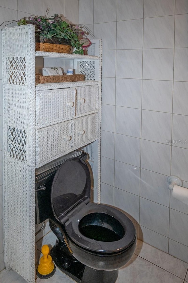 bathroom with tile patterned flooring, tile walls, and toilet