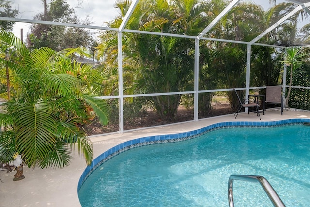 view of pool with glass enclosure and a patio