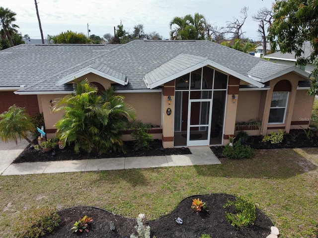 single story home featuring a sunroom and a front lawn