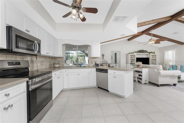 kitchen featuring lofted ceiling with beams, white cabinetry, kitchen peninsula, and appliances with stainless steel finishes