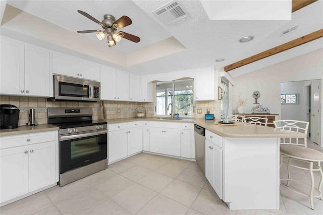 kitchen with white cabinets, decorative backsplash, a breakfast bar, and stainless steel appliances