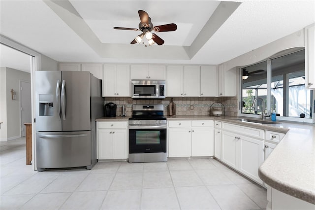 kitchen with white cabinets, a raised ceiling, sink, tasteful backsplash, and stainless steel appliances