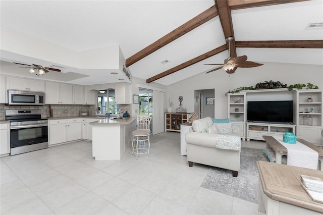 kitchen featuring a breakfast bar, backsplash, vaulted ceiling with beams, white cabinetry, and stainless steel appliances