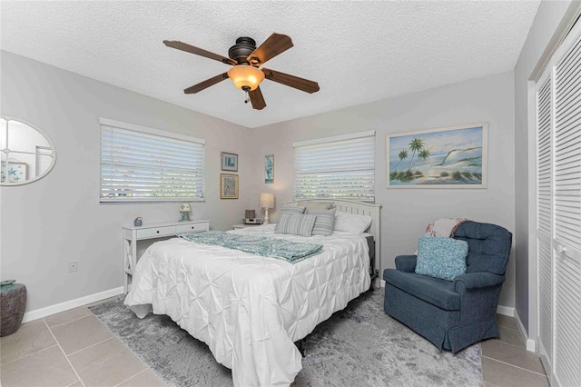 tiled bedroom with multiple windows, a textured ceiling, a closet, and ceiling fan