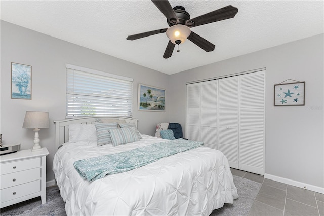 tiled bedroom with a textured ceiling, a closet, and ceiling fan