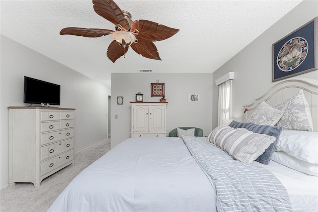 bedroom featuring a textured ceiling, light colored carpet, and ceiling fan