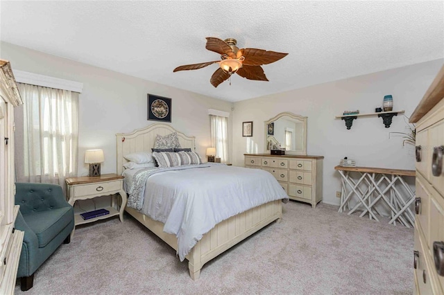 bedroom featuring a textured ceiling, light colored carpet, and ceiling fan