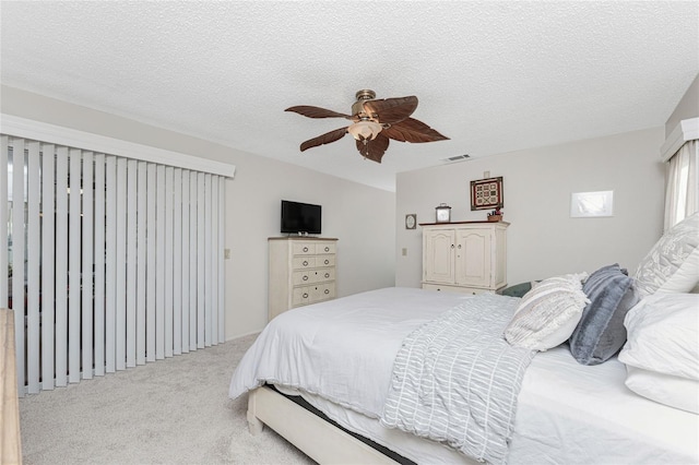 bedroom with ceiling fan, light carpet, and a textured ceiling