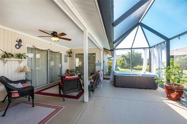 view of patio / terrace featuring a lanai, ceiling fan, and a hot tub