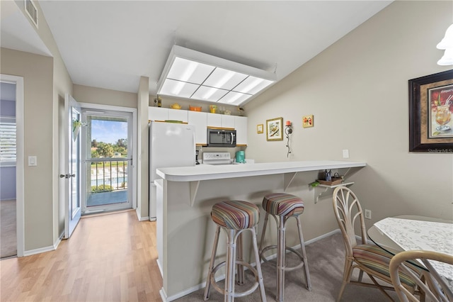 kitchen featuring white cabinetry, kitchen peninsula, light hardwood / wood-style floors, white appliances, and a breakfast bar area