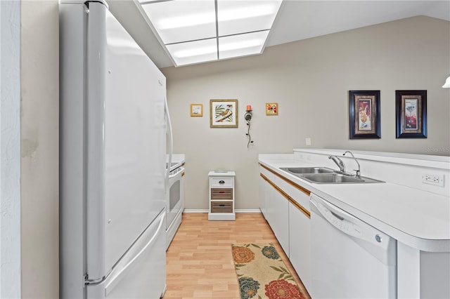 kitchen with white appliances, sink, vaulted ceiling, light wood-type flooring, and white cabinetry