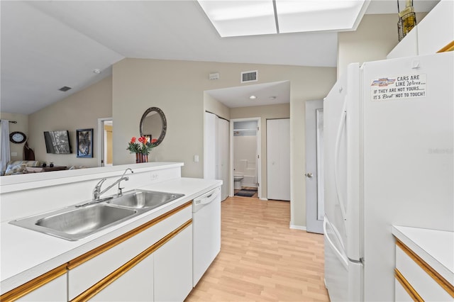 kitchen with light wood-type flooring, white appliances, vaulted ceiling, sink, and white cabinetry