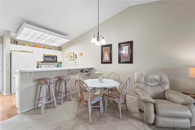 dining space featuring light wood-type flooring, an inviting chandelier, and vaulted ceiling