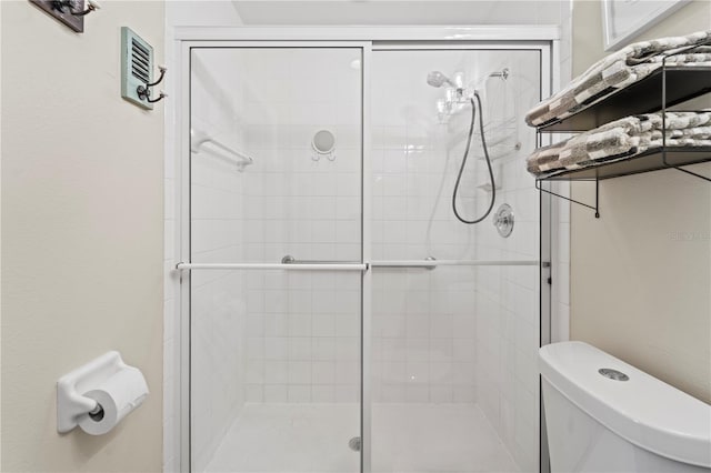 bathroom with toilet and a shower with door