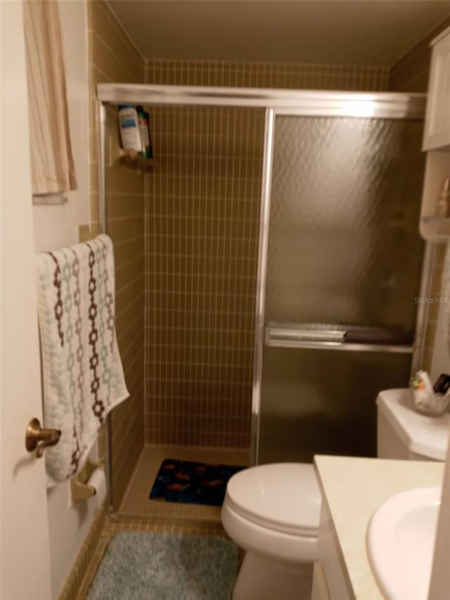 bathroom with tile patterned flooring, vanity, toilet, and walk in shower