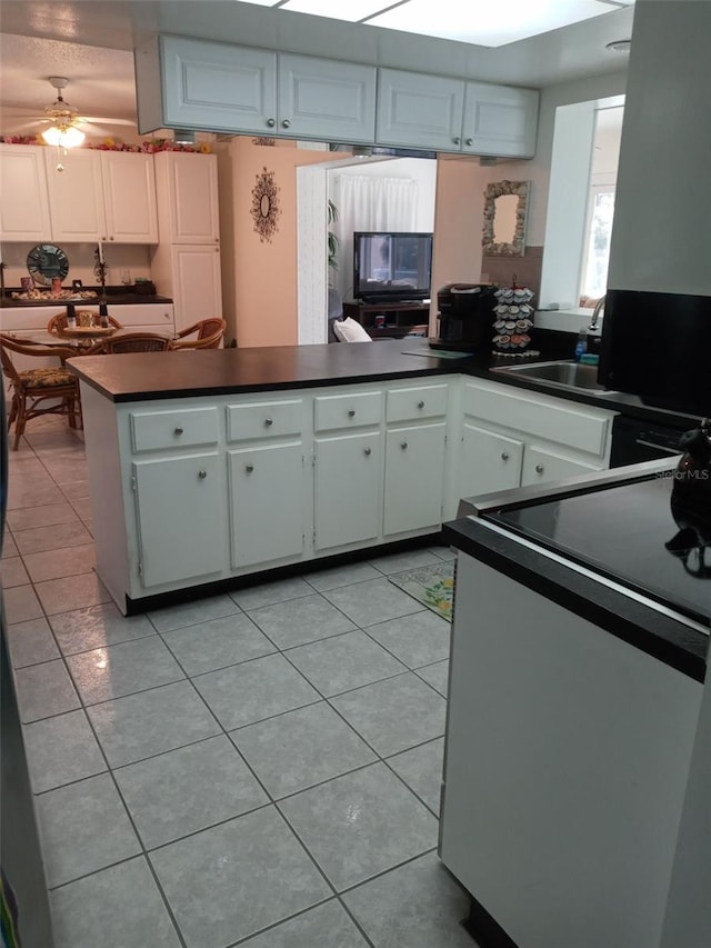 kitchen featuring kitchen peninsula, ceiling fan, light tile patterned floors, stainless steel range oven, and white cabinetry