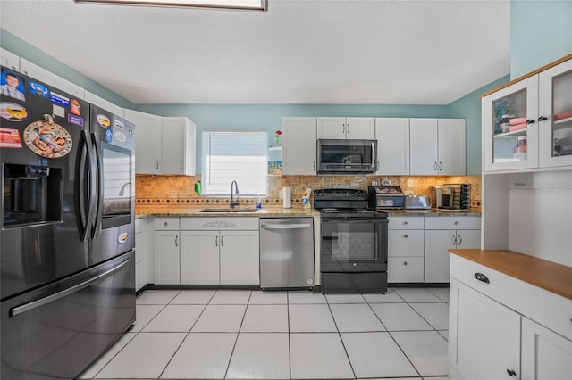 kitchen featuring backsplash, sink, light tile patterned floors, appliances with stainless steel finishes, and white cabinetry