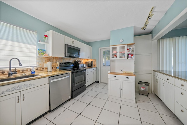 kitchen with sink, decorative backsplash, light tile patterned floors, white cabinetry, and stainless steel appliances