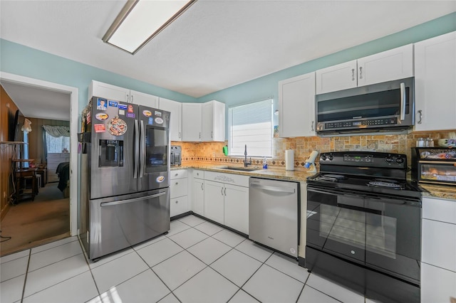 kitchen featuring backsplash, white cabinets, sink, light tile patterned floors, and appliances with stainless steel finishes