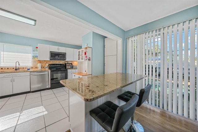 kitchen with backsplash, white cabinets, sink, appliances with stainless steel finishes, and light stone counters