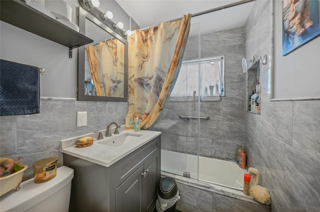 full bathroom featuring vanity, shower / bath combination with glass door, tile walls, toilet, and lofted ceiling