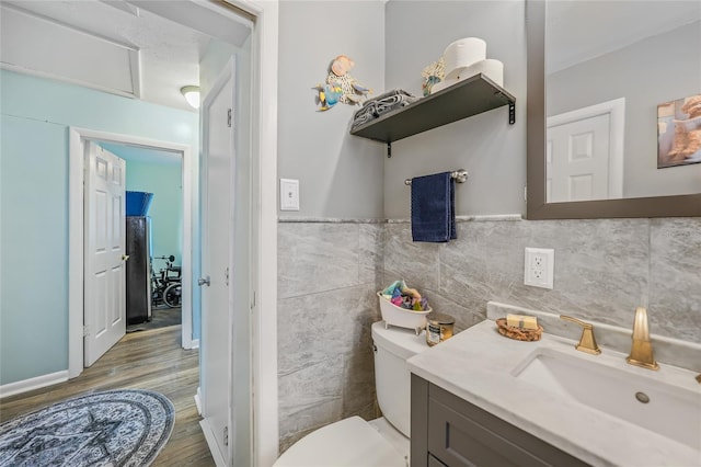 bathroom featuring vanity, hardwood / wood-style flooring, toilet, and tile walls